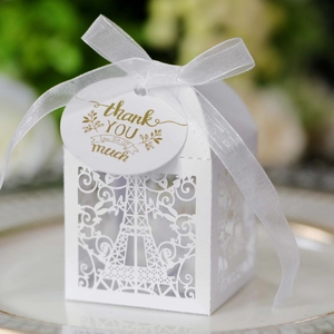 Macro view of white laser-cut Eiffel Tower favor box with thank you tag and ribbon