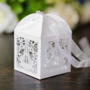 Detailed close-up of a white laser-cut Eiffel Tower favor box with elegant white ribbon