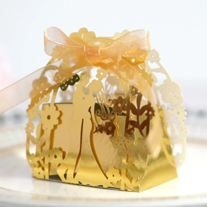Detail of laser-cut gold wedding favor box with romantic silhouette and organza ribbon