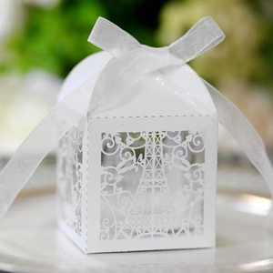 Close-up of white laser-cut wedding favor box with Eiffel Tower design and ribbon
