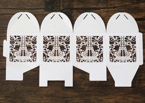Detailed flat lay of white laser-cut Eiffel Tower wedding favor box on wooden background