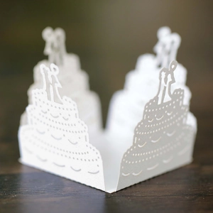 Close-up of white laser-cut hollow wedding cake favor box with bride and groom silhouette