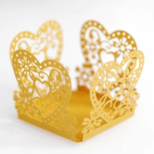 Detail of laser-cut heart pattern on a gold pearlescent paper wedding favor box