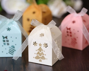 Detailed laser-cut Christmas favor boxes with snowflake patterns and white ribbon bows