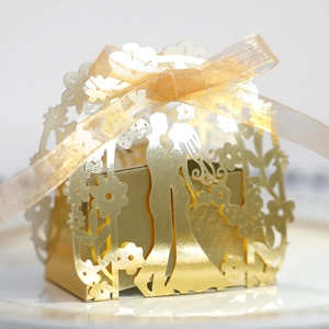 Detailed laser-cut gold wedding favor box featuring bride and groom silhouette and ribbon