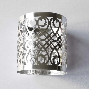 Macro shot of silver hollow metal napkin ring with geometric cutout pattern