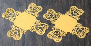 Detail of laser-cut heart pattern on golden pearlescent paper for wedding candy boxes