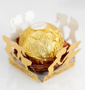 Macro detail of laser-cut gold cupcake wrappers featuring romantic couple silhouettes