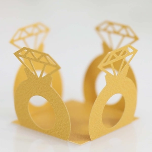 Detail showing the intricate laser-cut diamond ring design on golden favor boxes
