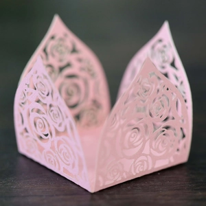 Close-up of pink laser-cut hollow rose candy box on dark wood background