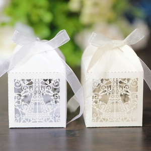 Detailed laser-cut Eiffel Tower favor boxes with elegant white silk ribbon bows