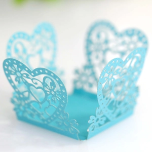 Detail of light blue laser-cut cupcake wrapper with intricate heart and floral patterns