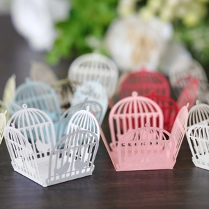 Macro view of laser-cut birdcage candy boxes in various colors for wedding favors