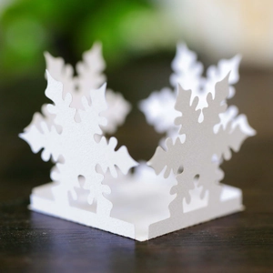 Detail of white hollow-out snowflake favor box for Christmas candies on wooden surface