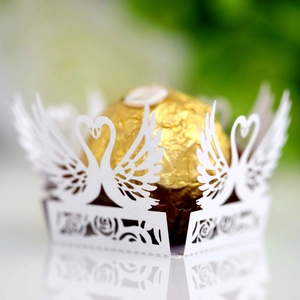 Macro detail of white laser-cut cupcake wrapper with swan design for wedding candies