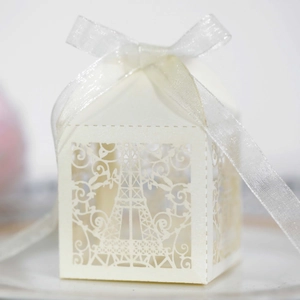 Detail of laser-cut Eiffel Tower favor box in cream paper with a white satin ribbon