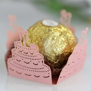 Macro shot of laser-cut pink paper cupcake liner with bride and groom silhouette detail