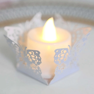 Vue macro d'un photophore papillon ajouré blanc avec bougie LED à lumière chaude