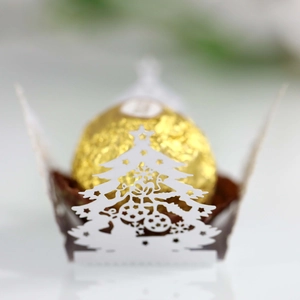 Close-up of laser-cut hollow Christmas tree candy box with golden ball chocolate