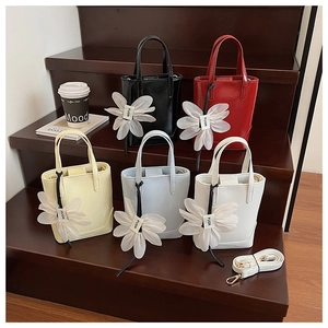 Detailed view of bucket bags in five colors with floral charms and detachable straps