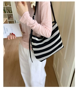 Détail d'un sac cabas en maille à rayures noires et blanches avec bretelles en cuir