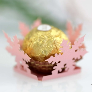 Detail of pink laser-cut snowflake paper wrapper holding a gold foil chocolate ball