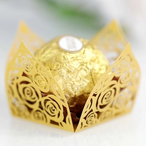 Macro detail of laser-cut gold rose pattern lace wrapper for chocolate and cupcakes
