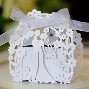 Close-up of white laser-cut wedding favor box with bride and groom silhouette and ribbon