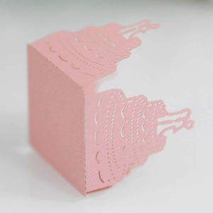 Detail of pink laser-cut cupcake wrapper with elegant hollowed-out wedding cake patterns