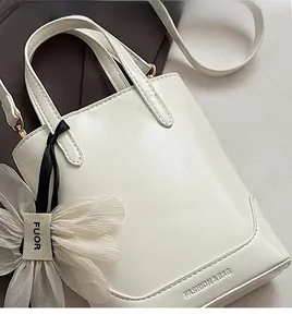 Macro shot of creamy white bucket bag featuring floral charm and embossed logo detail