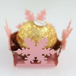 Pink laser-cut snowflake candy box holding a chocolate truffle for wedding party decoration