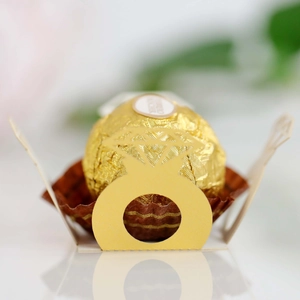 Close-up of laser-cut gold ring-shaped hollow candy box with chocolate for weddings