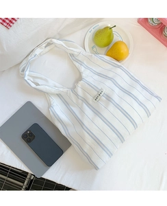 Detail of blue and white striped canvas tote bag with Korean tag on white bedsheet