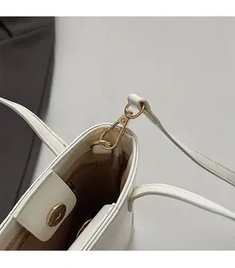 Detail of white bucket bag with gold magnetic closure and interior zipper pocket