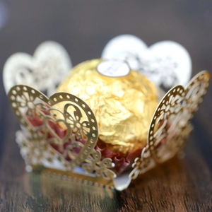 Macro shot of gold heart-shaped laser-cut hollow paper holder for chocolate gift