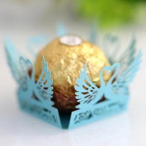 Macro view of light blue laser-cut paper candy box featuring elegant swan heart design