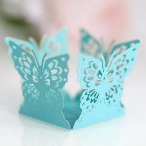 Macro shot of light blue laser-cut butterfly cupcake wrapper with intricate wing patterns