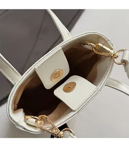Close-up of white bucket bag featuring a gold magnetic closure and premium interior detail
