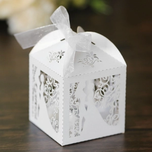Detail of white laser-cut wedding favor box with Mr & Mrs silhouette and organza ribbon