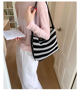 Détail du sac cabas en tricot rayé noir et blanc avec bandoulière en cuir noir élégant