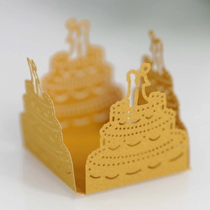 Macro shot of gold laser-cut paper wedding cake lantern with bride and groom silhouettes