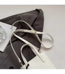 Detail of white leather bucket bag featuring adjustable straps and gold-tone hardware