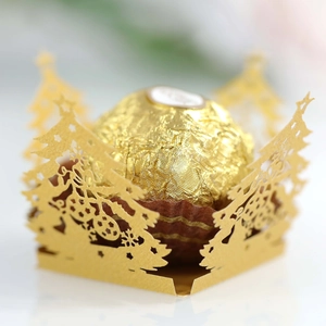 Macro shot of laser-cut gold Christmas tree paper lace for chocolate packaging