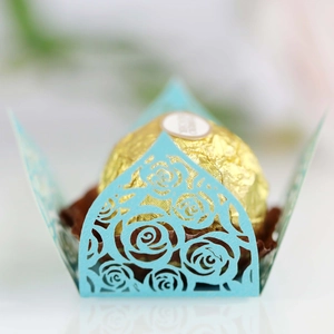 Macro shot of light blue laser-cut rose hollow cupcake wrappers for wedding chocolates