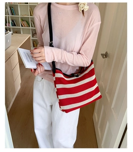 Close-up of red and white striped knit hobo bag with adjustable black leather strap