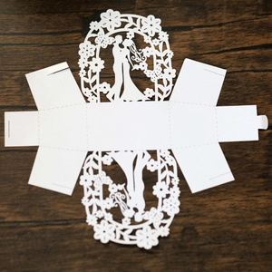 Flat lay of a white laser-cut wedding candy box with romantic couple silhouette detail