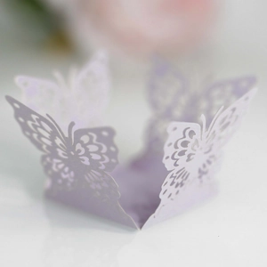 Macro detail of lavender laser-cut paper butterfly with intricate hollow-out floral patterns