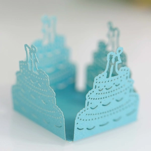 Macro detail of laser-cut light blue paper cake lace featuring a romantic couple silhouette