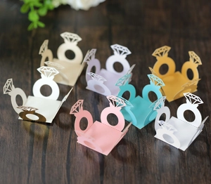 Laser cut hollow diamond ring shape paper candy boxes in multiple colors on a wood surface