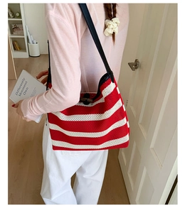 Close-up of red and white striped knitted tote bag featuring a black leather strap and bamboo toggle
